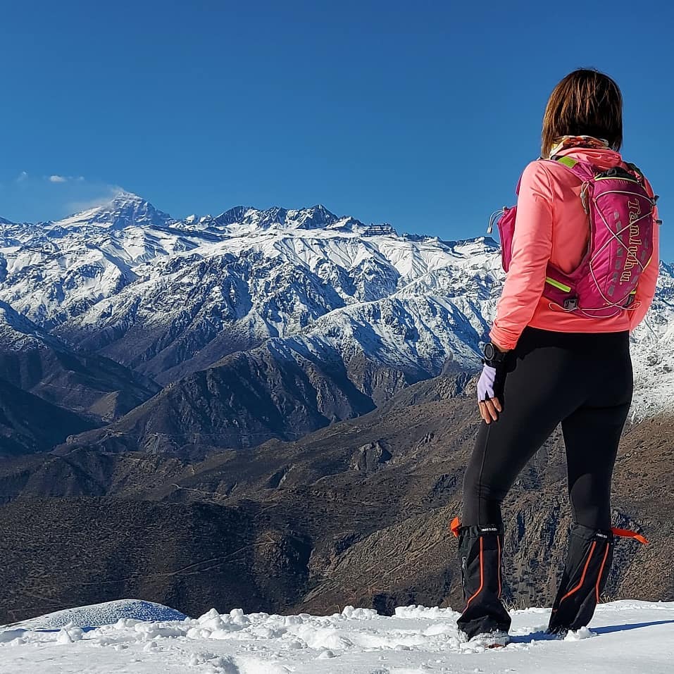Mujer en la nieve observando el monte Aconcagua frente a ella.