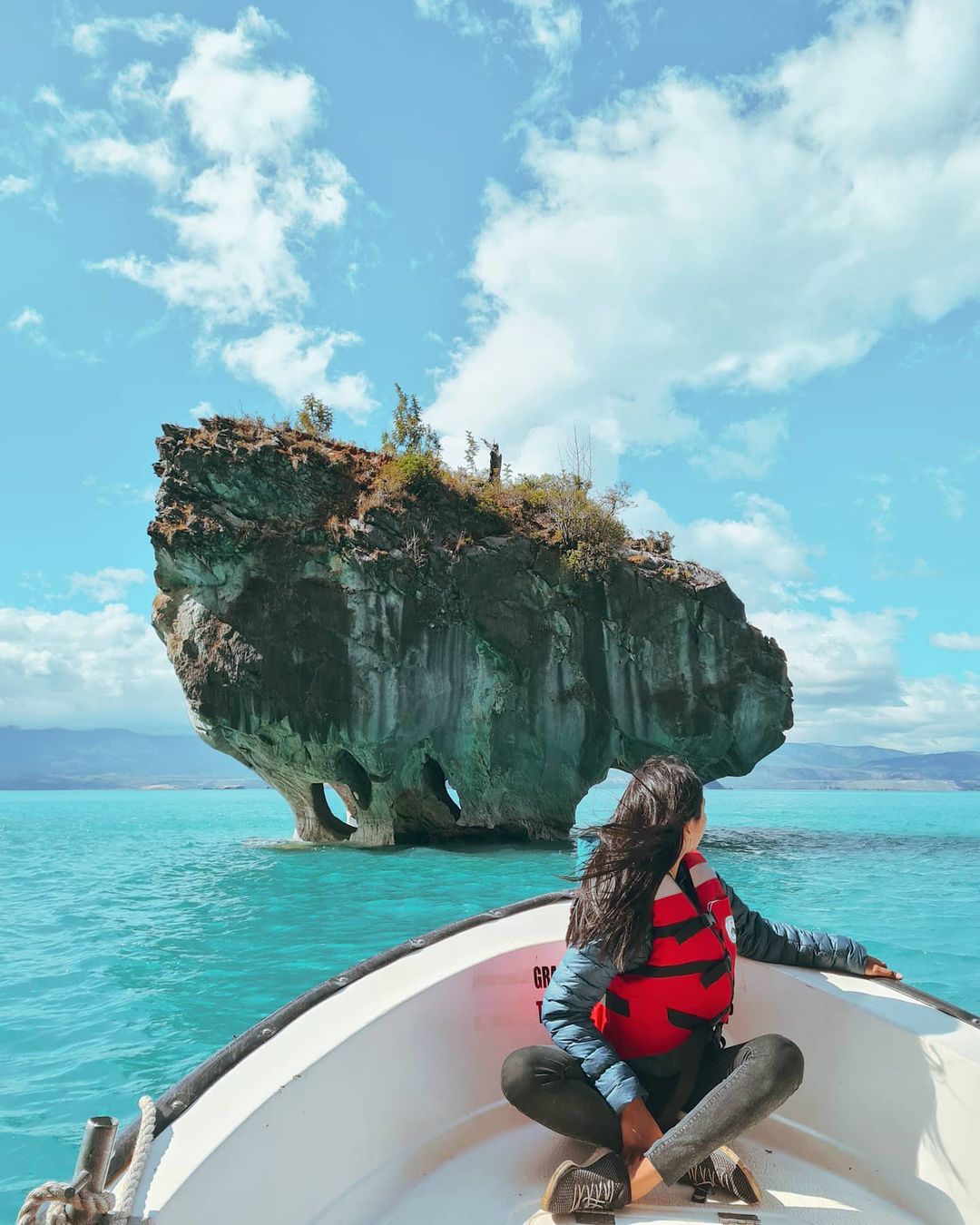 Woman in boat heading towards a Marble Chapel, southern Chile