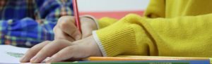 Child writing in his notebook in class