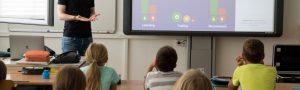 teacher in front of his classroom working with a classroom interactive tool