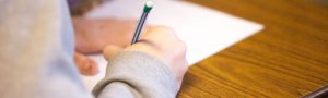 student at his desk writing on a piece of paper