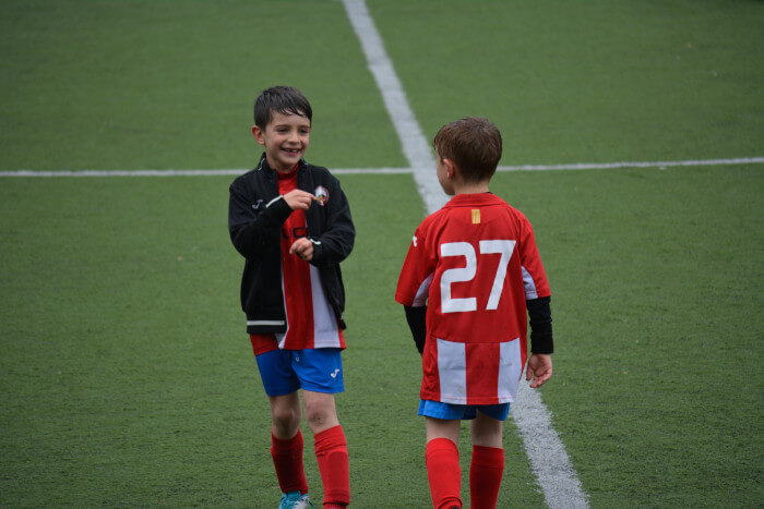 2 crianças em uniformes do futebol na chuva