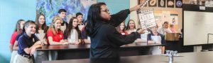 teacher with a clapboard in front of her students shooting a video