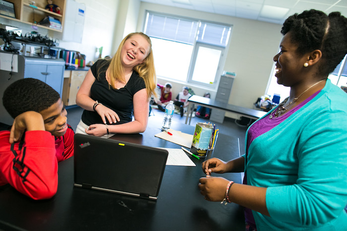 Happy students and teacher with laptop