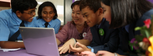 Several students with teacher looking at laptop