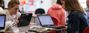 Student focused on reading and working on laptop