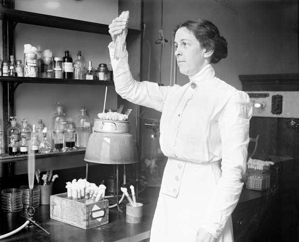 Alice C. Evans holding a test tube while working in a lab.  It was in a lab like this one where she discovered the brucellosis bacteria