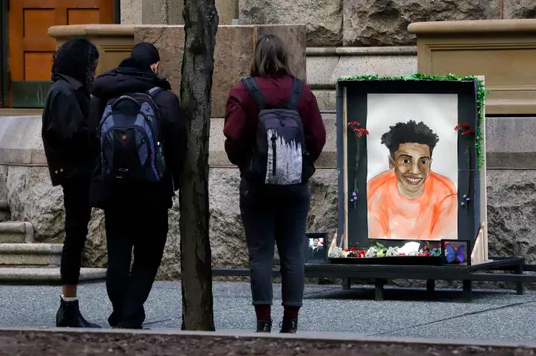 Community members gather around a memorial drawing of Antwon Rose outside of the Allegheny County Police Department awaiting Michael Rosfeld's preliminary hearing. The artist of the memorial drawing is unknown.