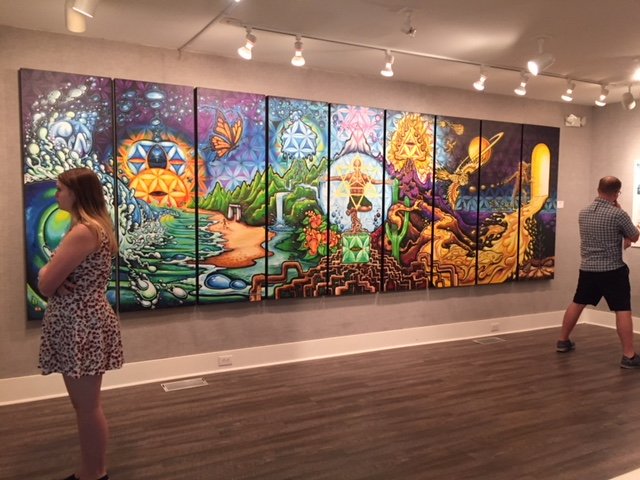 Visitors admiring Drew Brophy's work with his nine-panel mural "A Life Well Lived" in the background. It began as a mural project for Keen footwear.