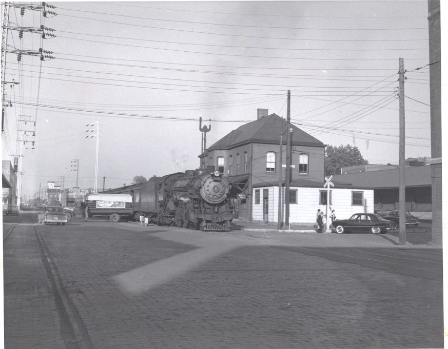 Passenger train pauses in Huntington, 1956. Seems as if a grandfather has come to town for a visit, while a Railway Express Agent unloads packages. Photo by Herbert H. Harwood, Jr., from the Bob Withers Collection. (2013).