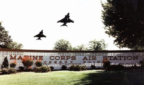 This is the main gate to MCAS Cherry Point with two AV-8B Harriers flying over.