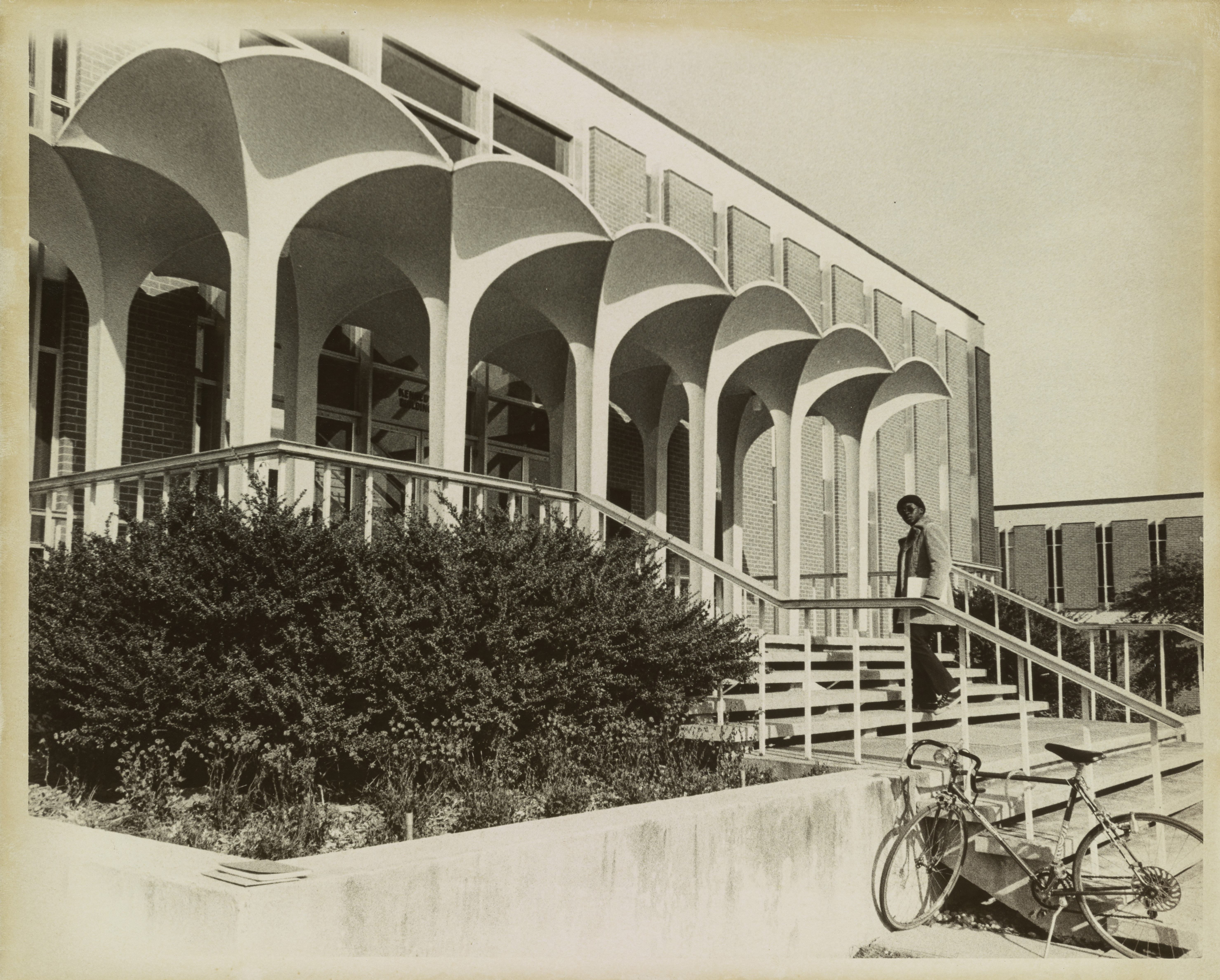 The Kennedy Building with a student on the steps. Undated, black and white image.