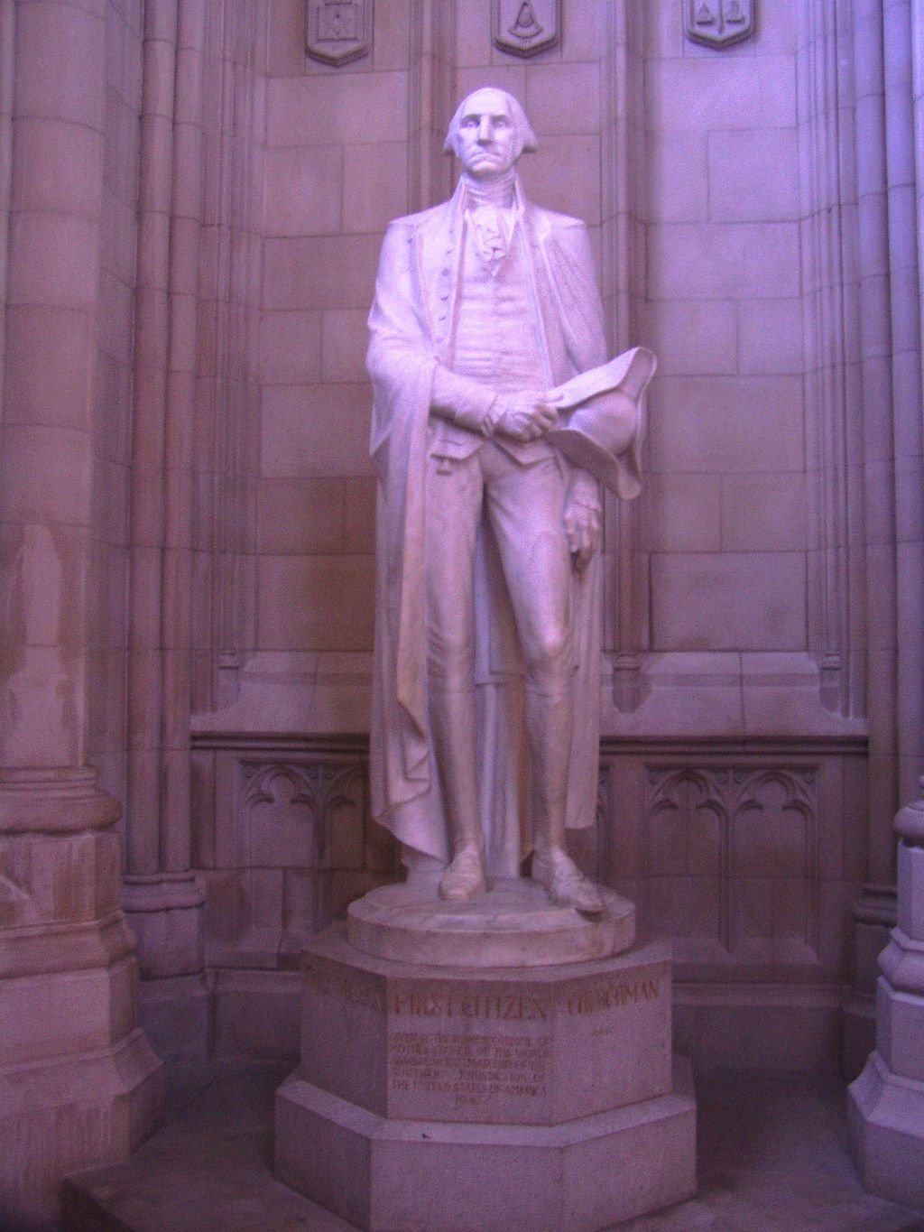 A statue of President George Washington, who planned the Cathedral, stands in an alcove where symbols such as his coat of arms can be found. Photo by Danvera, English Wikimedia.