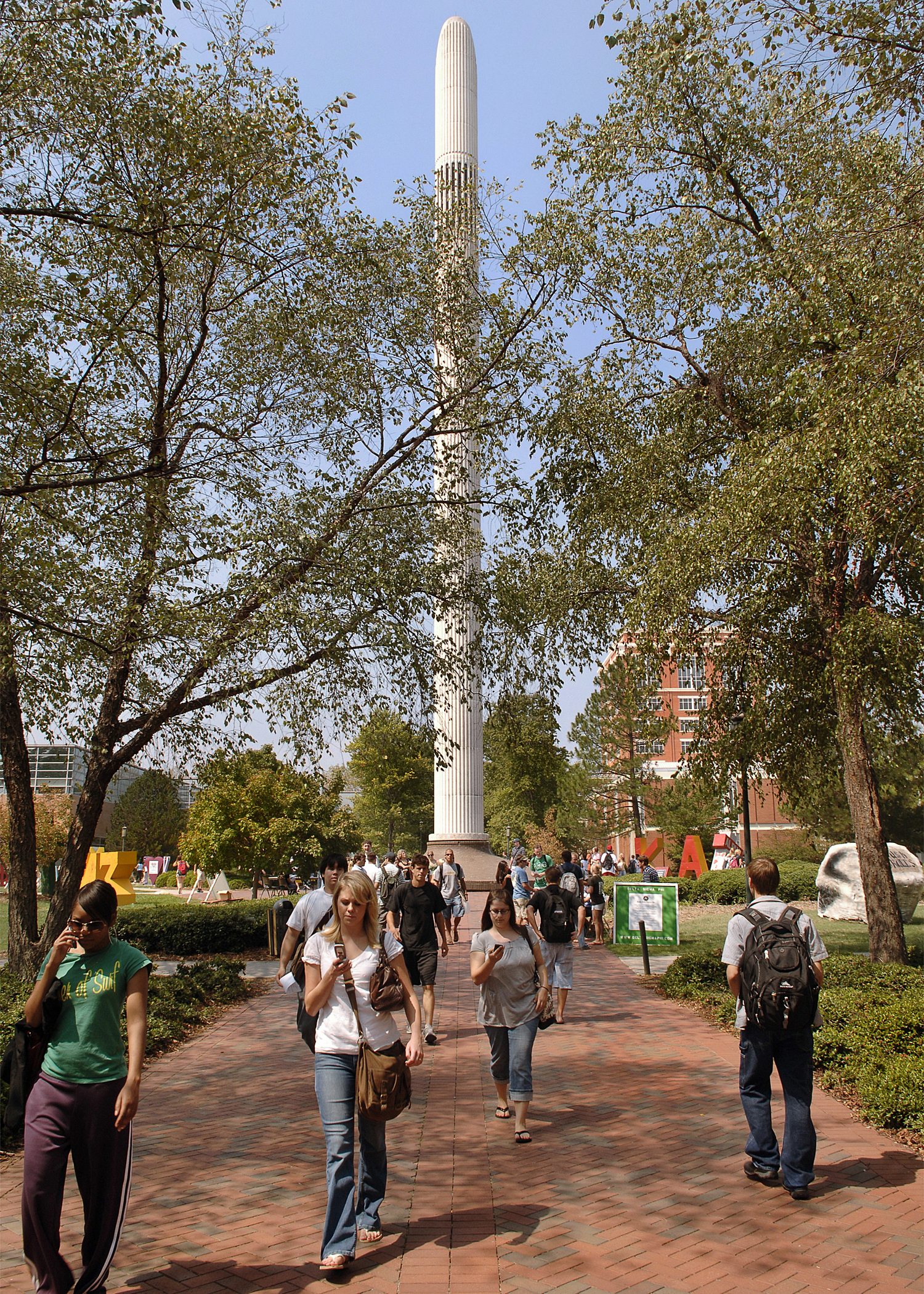 The Belk Bell Tower in September 2007. In front of the tower students walk on a brick path and trees line the path.