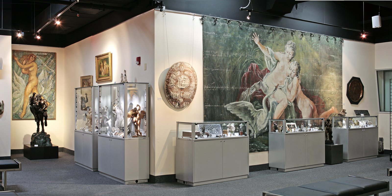 A variety of objects including tapestries, glass display cases, and paintings fill a gallery space.