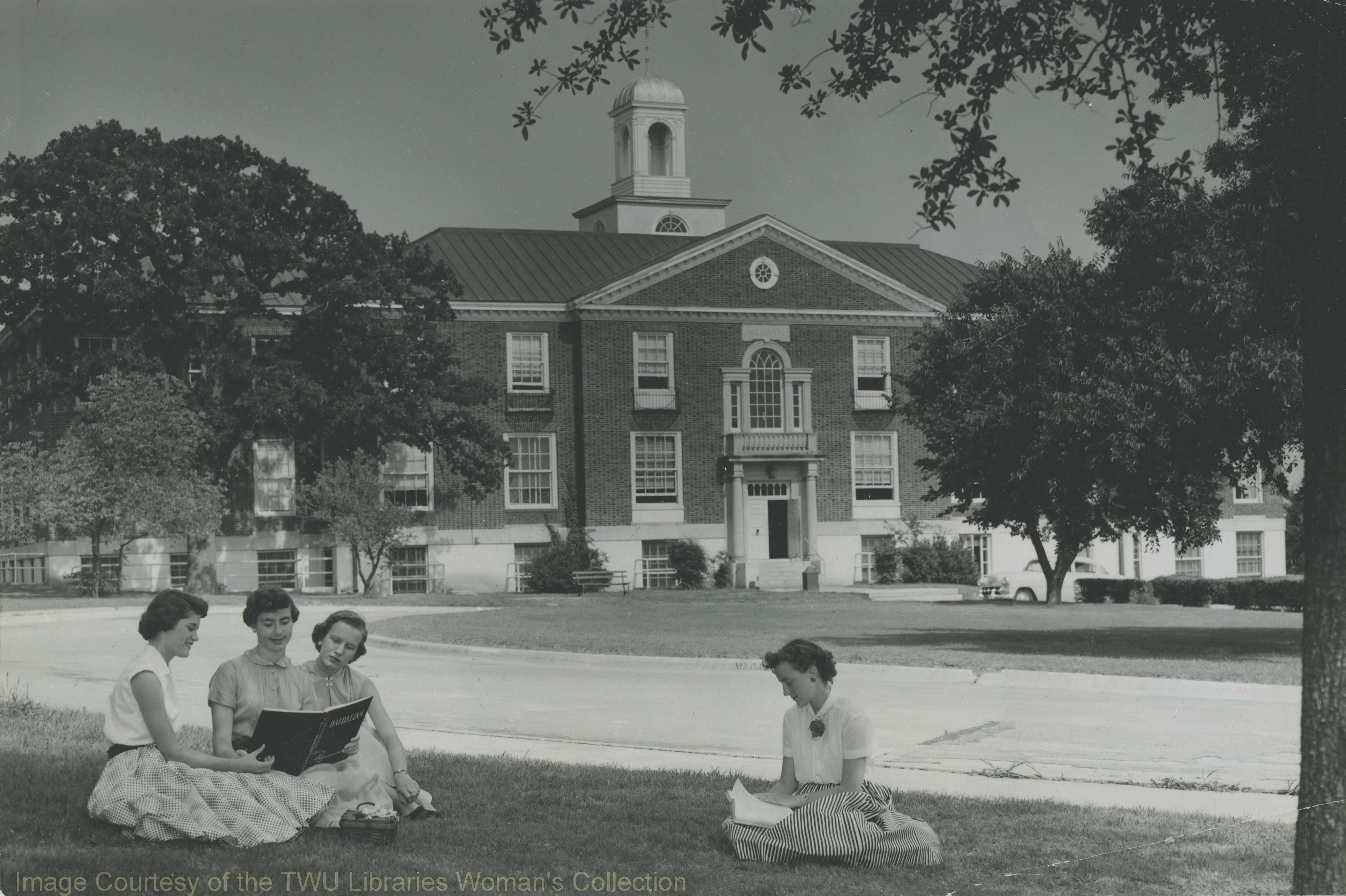 Students looking at a Daedalian yearbook in front of the west side of Bralley Memorial Library. Bralley opened in 1927 and was demolished in 1996. (Photo:1950s, Courtesy TWU Woman's Collection)