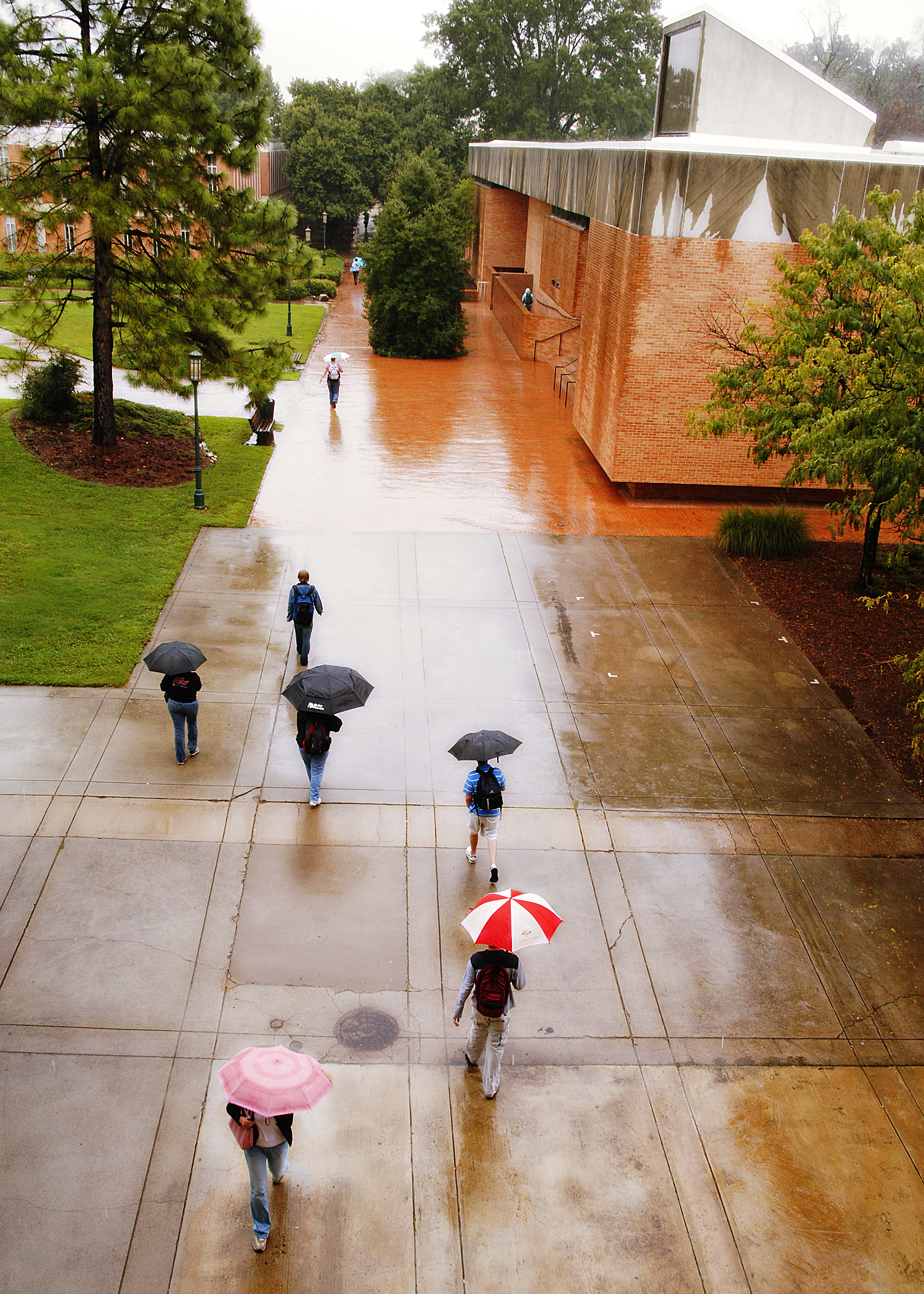 Rowe Arts Building in 2006 on a rainy day from a distance. The sidewalk outside of the building is in the foreground, with students walking with umbrellas.