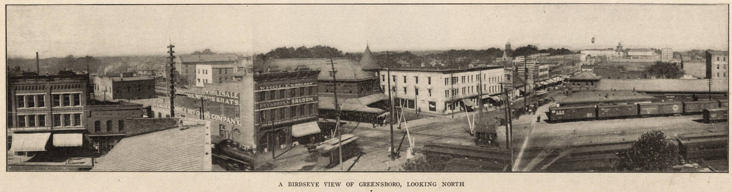 A panoramic view looking north from the railroad tracks into downtown Greensboro, showing in foreground the Cascade Saloon and Southern Railway station, among other buildings