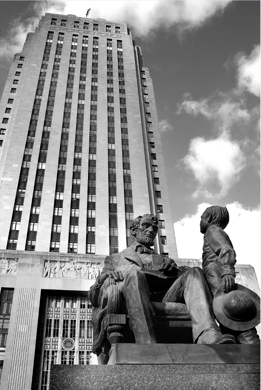 An image of the statue of President Abraham Lincoln and his son Tad on the South Plaza of City Hall, featuring City hall rising vertically in the background on the left-hand side.