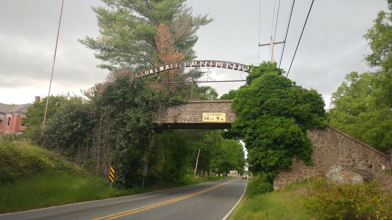 The sign for Old Stonewall above an ivy covered bridge built in 1940