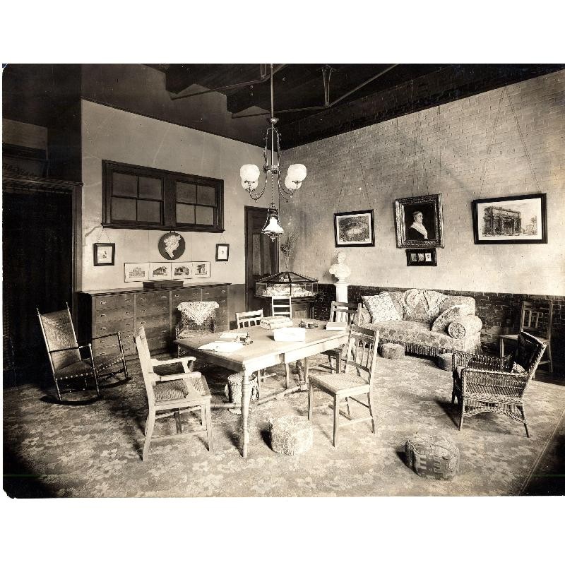 Black & White Photo. Victorian sitting room with four chairs around a table, sofa along the right hand wall.