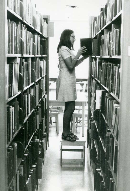Student re-shelving books, undated