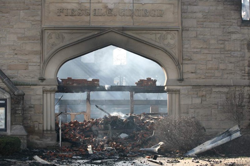 Sunlight shines through the entrance of the church illuminating the debris. 