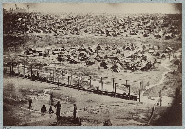 Displays the many tents constructed by prisoners and harsh conditions they suffered