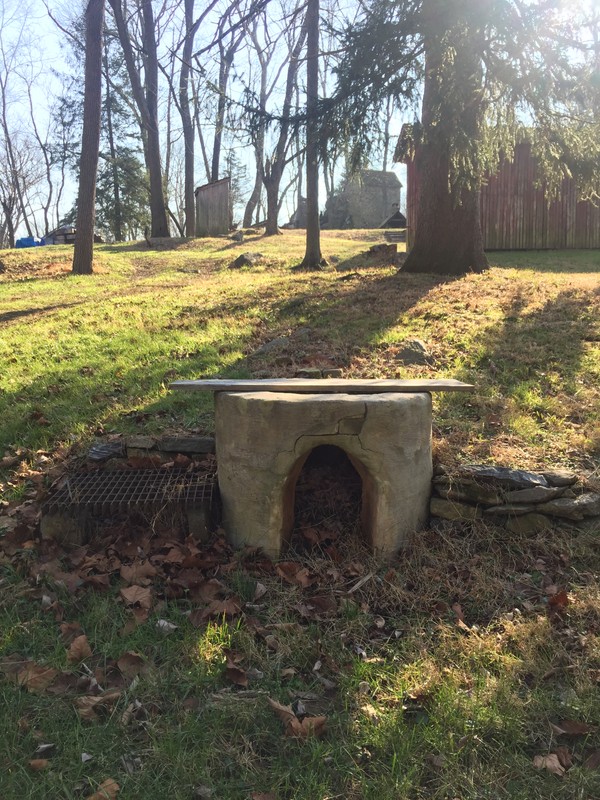 Image of clay kiln surrounding a large iron pot, with an arched fireplace at the base.