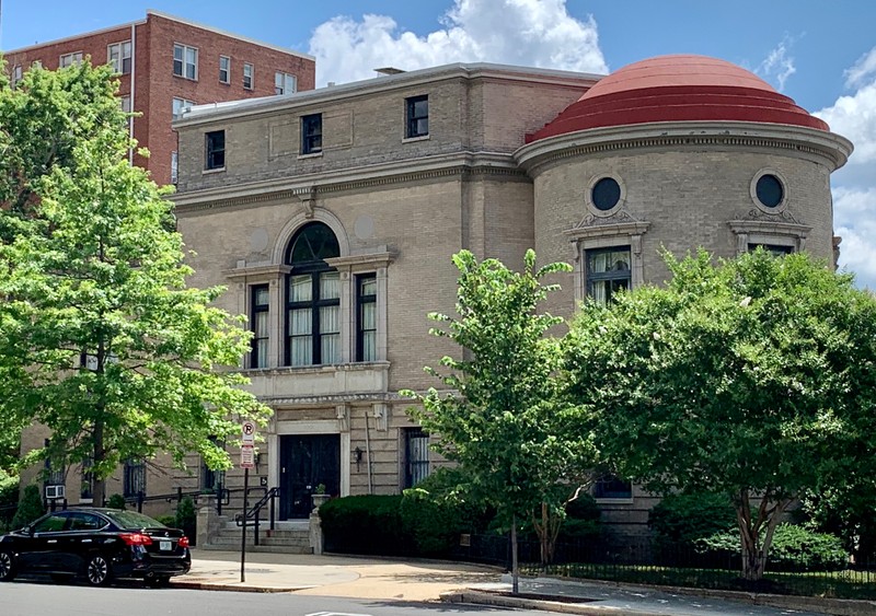 Off-center of the Congressional Club building from street, with trees in foreground.