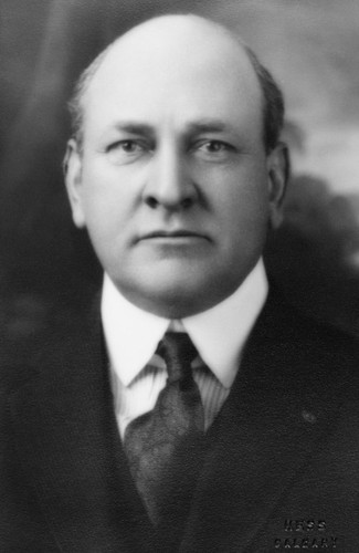 Black and white portrait of bald man wearing suit and tie