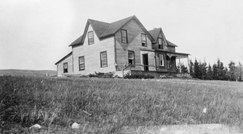 Black and white image of ranch house in open field