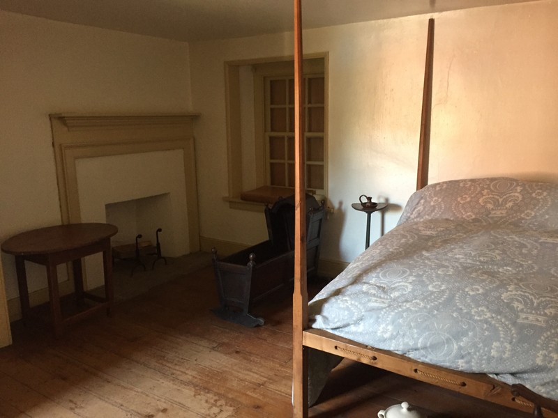 Image of a bedchamber with a high-post bed, baby cradle, and fireplace.