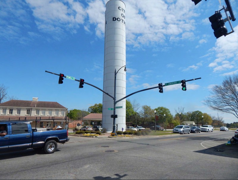 An image depicting the Dothan Dixie Standpipe. It is a White, 100ft tall, metal tower with the words "CITY OF DOTHAN" painted on the tower near the top.