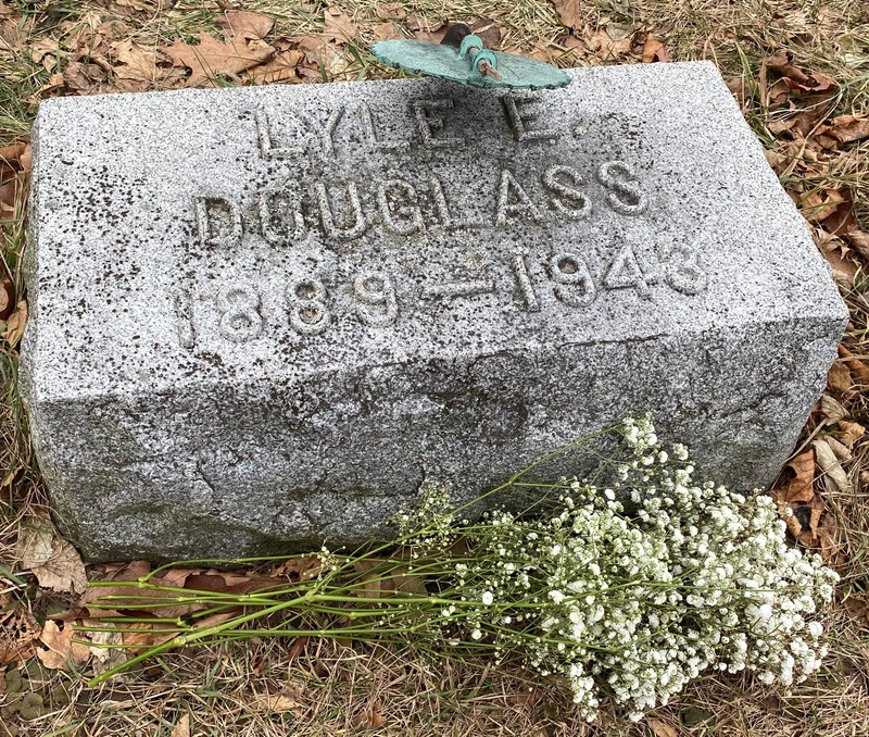 A gravestone a little less than a foot off the ground, inscribed as "Lyle E. Douglass 1889-1943" with a gravestone marker denoting his service in World War I.