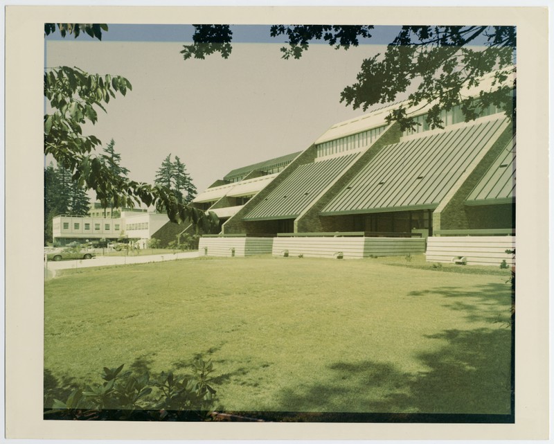 Color photograph depicts sloping metal and brick exterior of CDRC, set against backdrop of campus lawn and trees.