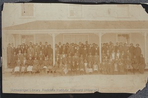 A sepita-toned photo of a number of black children and adults standing in rows