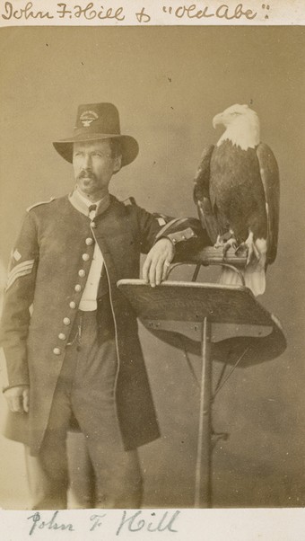 Carte-de-visite full-length portrait photograph of Old Abe the War Eagle, and handler, John F. Hill, made for the centennial in 1876. Old Abe served as the mascot for the 8th Wisconsin Infantry Regiment during the Civil War.  