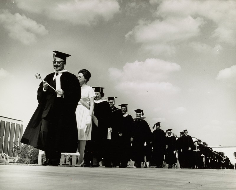 Pierre Macy leading commencement procession with faculty members behind him, 1965. Black and white photograph.