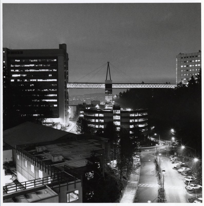  Black and white photograph of the Veterans Affairs Medical Center skybridge and support connecting to the University Hospital South above Campus Drive after dark.