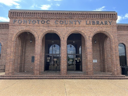 Exterior of library building, light brick and high arches run along the facade