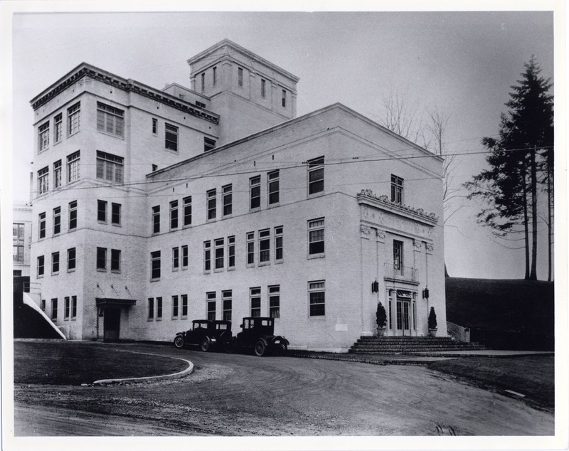 Black and white photograph of the exterior of Doernbecher Memorial Hospital for Children circa 1926, looking northwest. Several 1920s vehicles are visble at the side entrance.