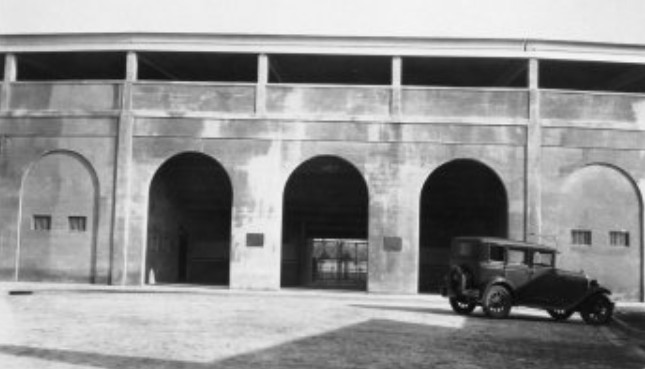 Baseball stadium with old car parked in front.