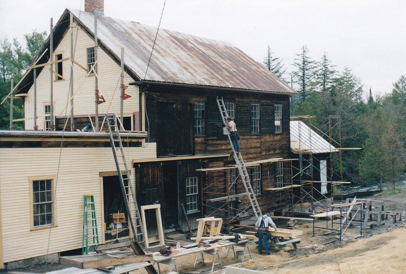 New clapboard siding being added to the mill's exterior by dedicated volunteers.