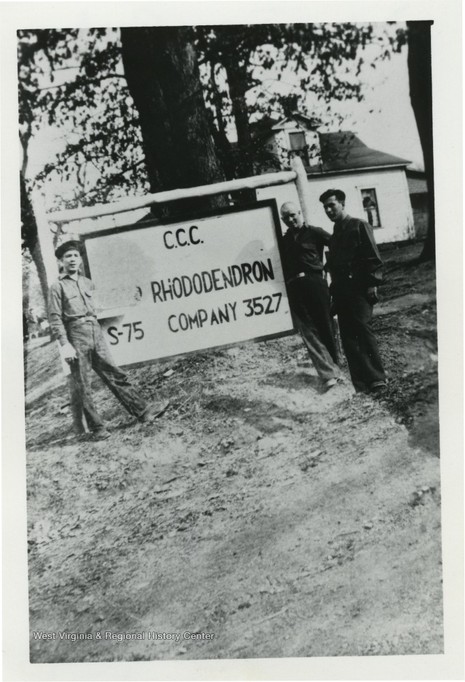 Three Camp Rhododendron members with the camp sign