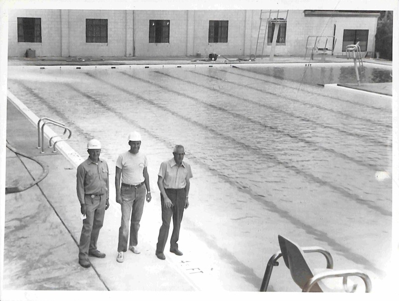 Three men standing beside Portales pool
