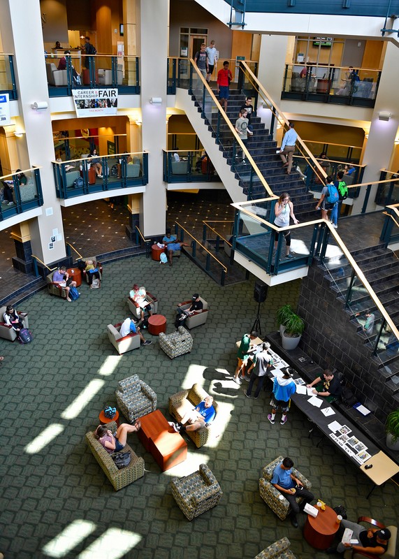 Atrium inside of the Popp Martin Student Union, shot from the third floor. View of seating and students below, the staircase, and second and third floor balconies.