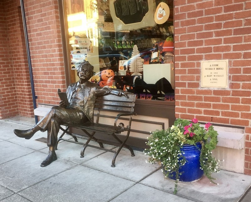 Photograph of the Mark Twain statue and historical marker on the sidewalk next to the bench.