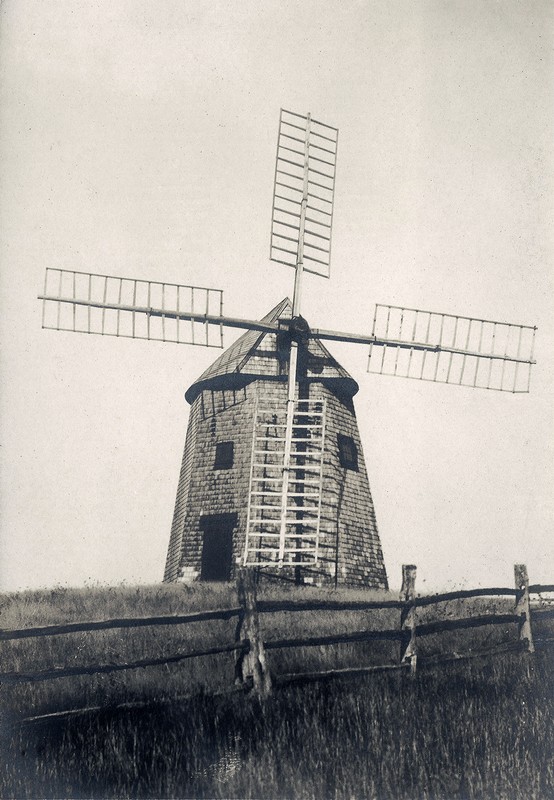 An antique (c. 1905) postcard of the Godfrey Windmill in its original location east of Stage Harbor Road.  This image was taken toward the end of the commercial life of this gristmill.