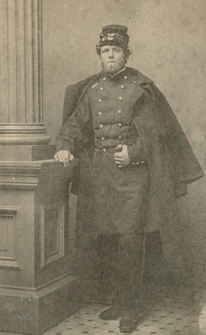 A carte-de-visite, full-length portrait photograph of Cassius Fairchild. He is shown wearing a dress uniform with cap and a cloak. 